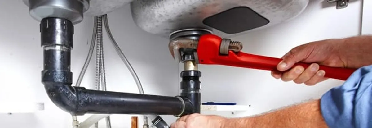 Garbage disposal repair technician tightening the sink drain and disposal connection in Dayton, OH